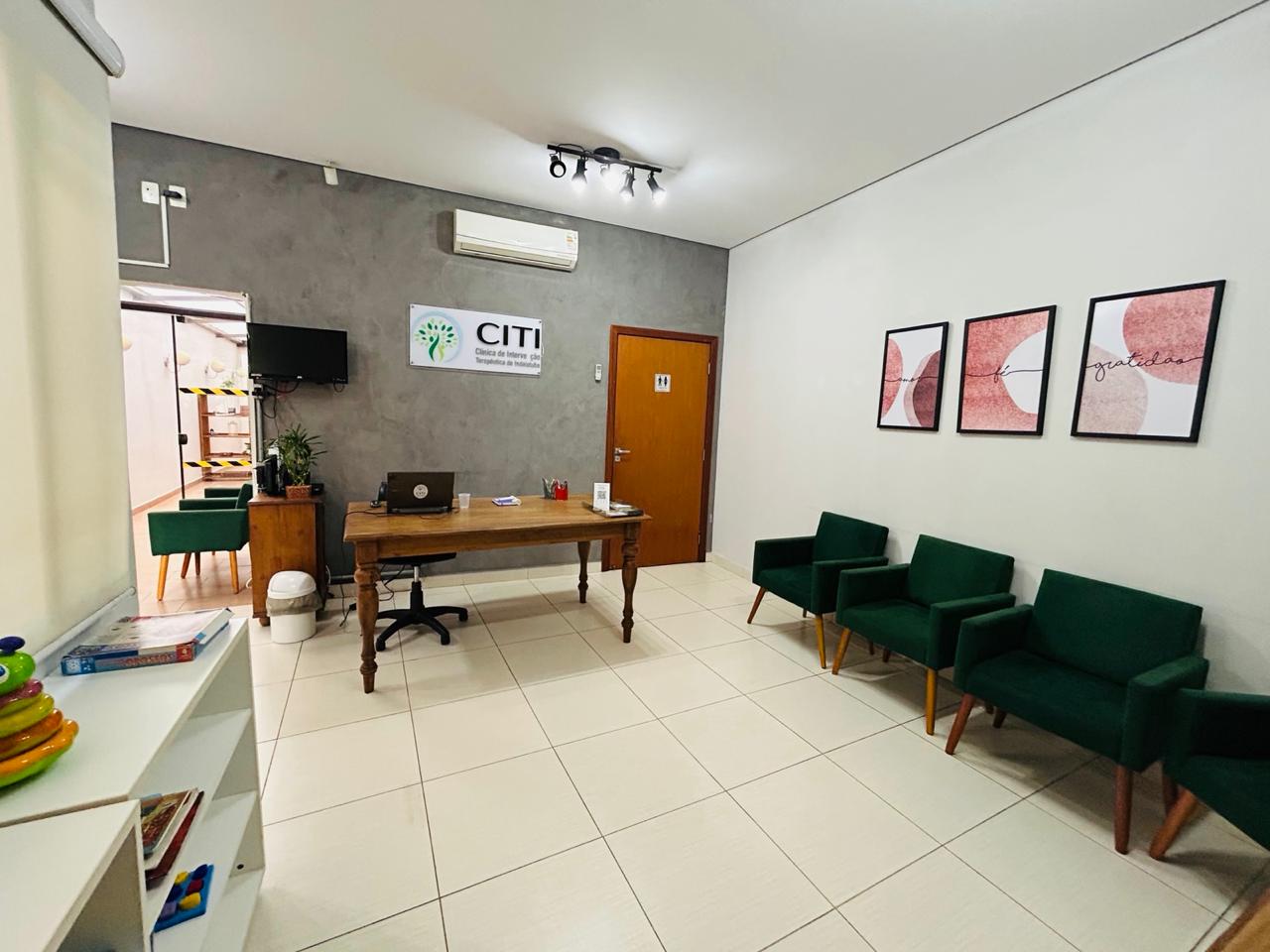 Recepção da Clínica CITI com poltronas verdes e mesa de atendimento